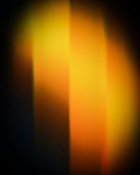 Soft bands of warm yellow and orange light, out of focus against the dark
